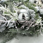 Decorative wreath with frosted branches and silver ornaments on a white background