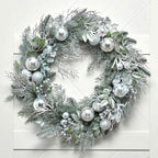 Decorative wreath with silver ornaments on a white wooden background