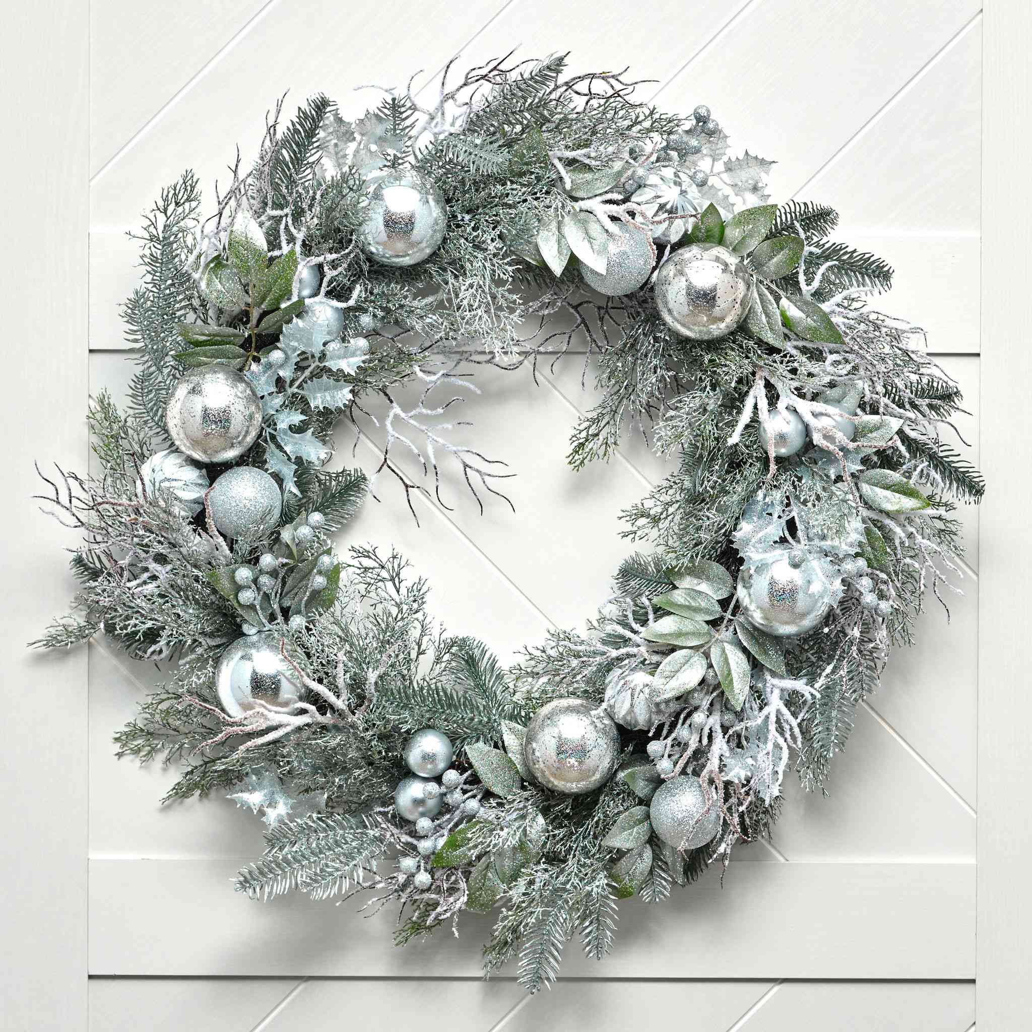 Decorative wreath with silver ornaments on a white wooden background