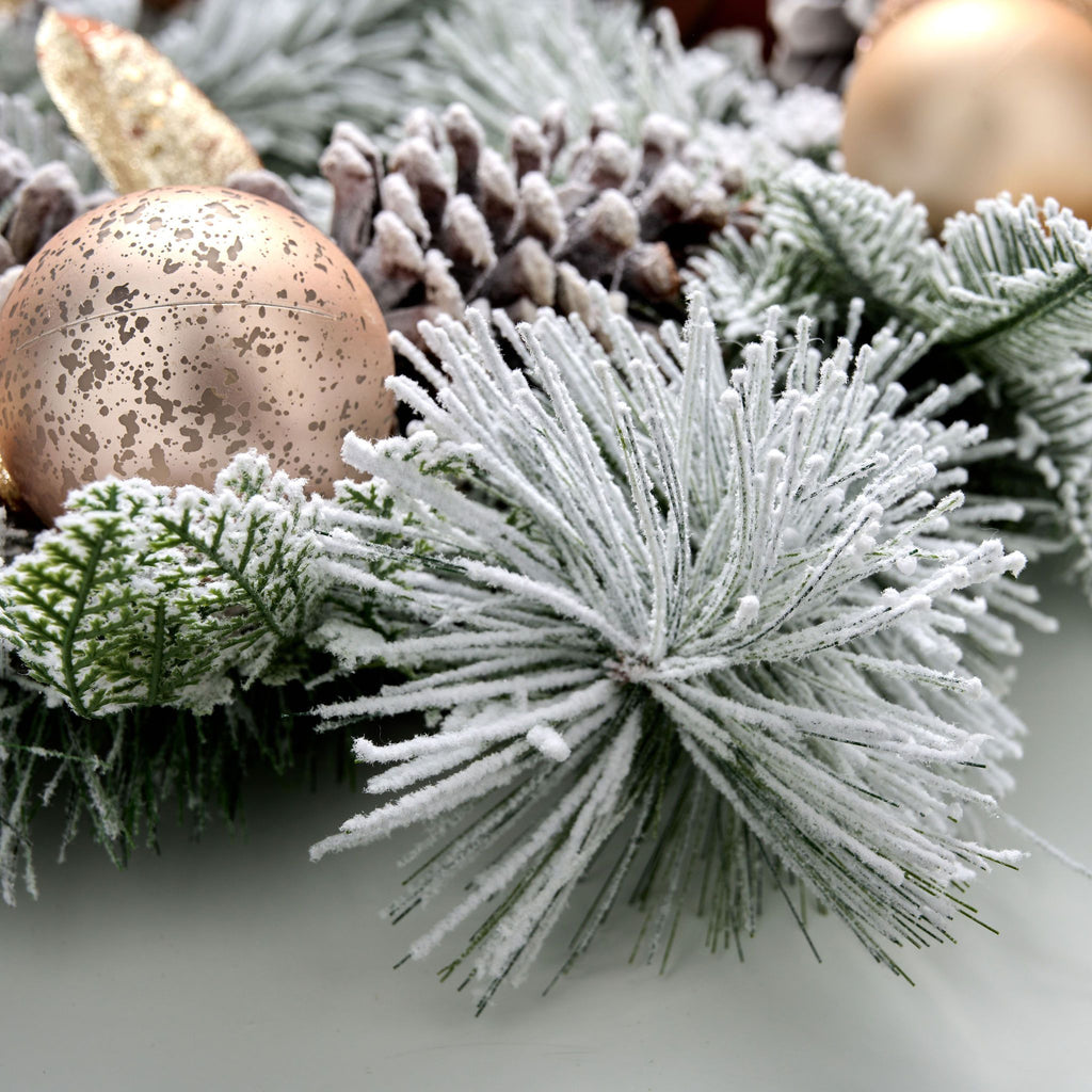 Decorative wreath with frosted pine cones and branches on a white background.