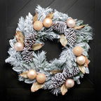 Decorative Christmas wreath with frosted pine branches, pinecones, and gold ornaments on a dark background.